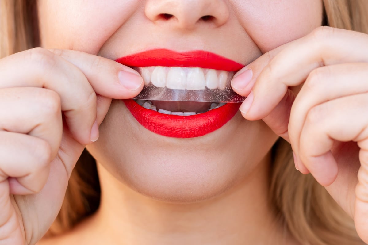 Woman holding a whitening strip, smiling